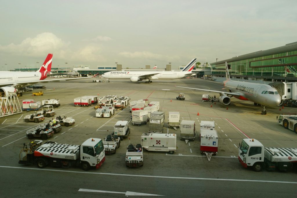 white and red trucks parked beside gray and white plane